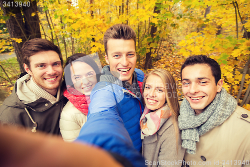 Image of group of smiling men and women in autumn park