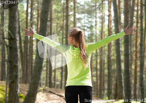 Image of happy woman in sport clothes raising hands