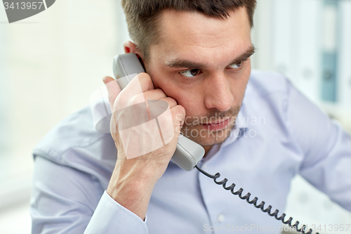 Image of face of businessman calling on phone in office