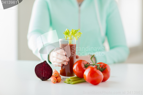 Image of close up of woman hands with juice and vegetables