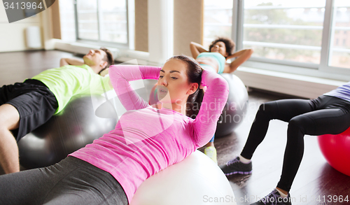 Image of happy people flexing abdominal muscles on fitball