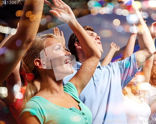 Image of smiling friends at concert in club