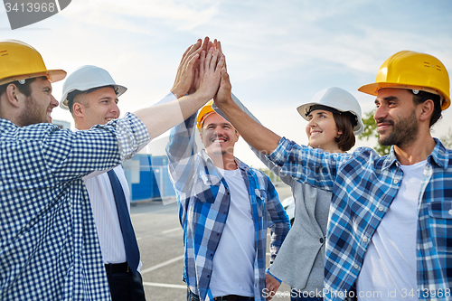 Image of close up of builders in hardhats making high five