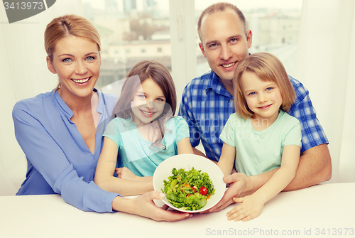 Image of happy family with two kids with salad at home