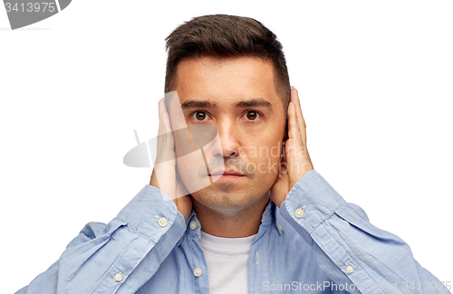 Image of face of man covering his ears with hands