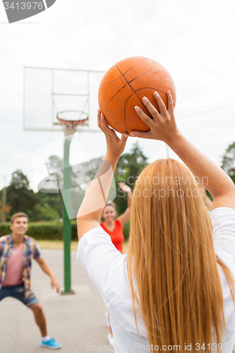 Image of group of happy teenagers playing basketball