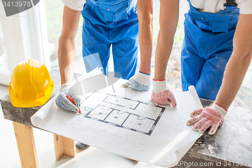 Image of close up of builders discussing blueprint