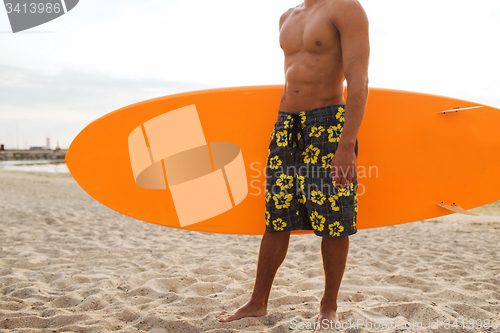 Image of close up of young man with surfboard on beach