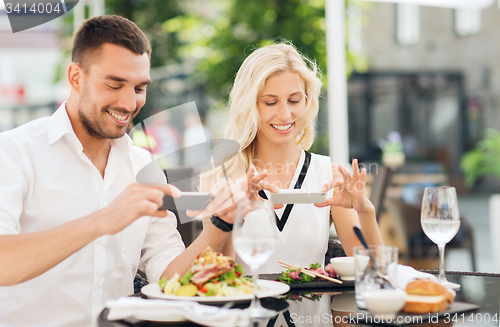 Image of happy couple with smatphone photographing food