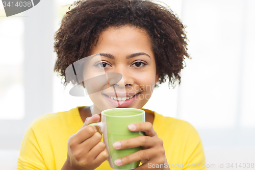 Image of happy african american woman drinking from tea cup