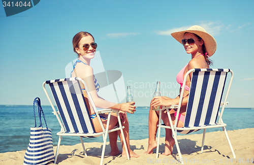 Image of happy women sunbathing in lounges on beach