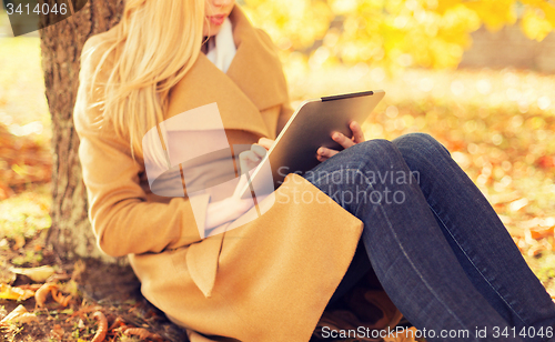 Image of young woman with tablet pc in autumn park