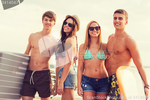 Image of smiling friends in sunglasses with surfs on beach