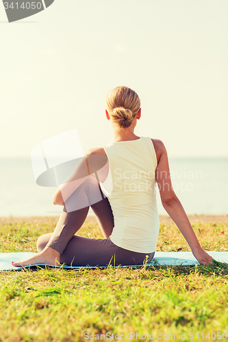 Image of woman making yoga exercises outdoors