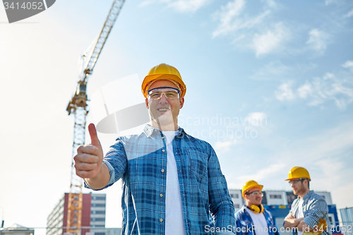 Image of group of smiling builders in hardhats outdoors