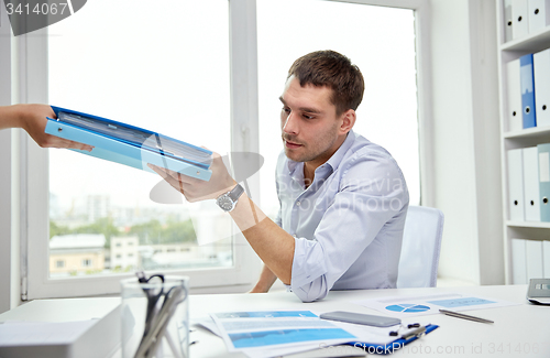 Image of businessman taking papers from secretary in office