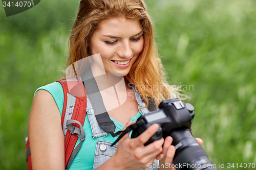 Image of happy woman with backpack and camera outdoors