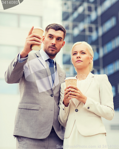 Image of serious businessmen with paper cups outdoors