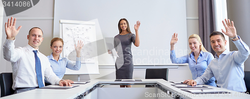 Image of group of businesspeople waving hands in office