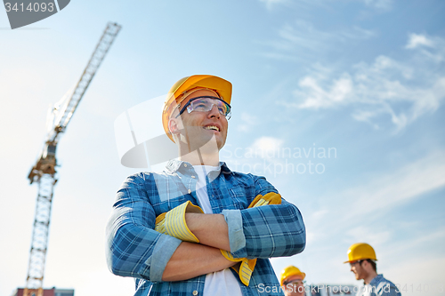 Image of group of smiling builders in hardhats outdoors