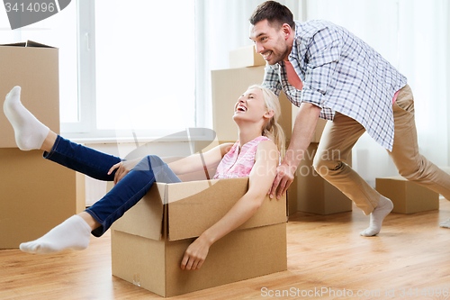 Image of couple with cardboard boxes having fun at new home