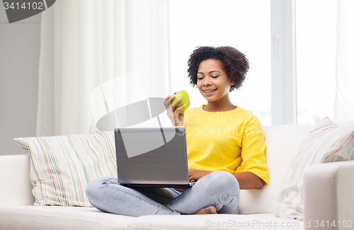 Image of happy african american woman with laptop at home