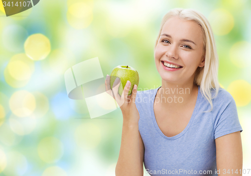 Image of happy woman eating green apple