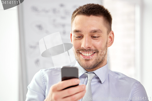 Image of young smiling businessman with smartphone