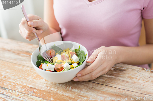 Image of close up of young woman eating salad at home