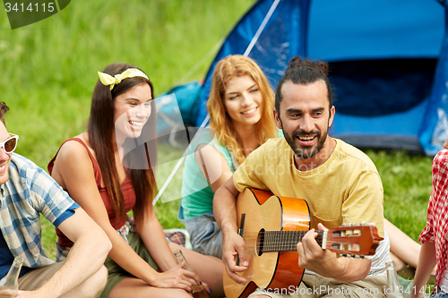 Image of happy friends with drinks and guitar at camping