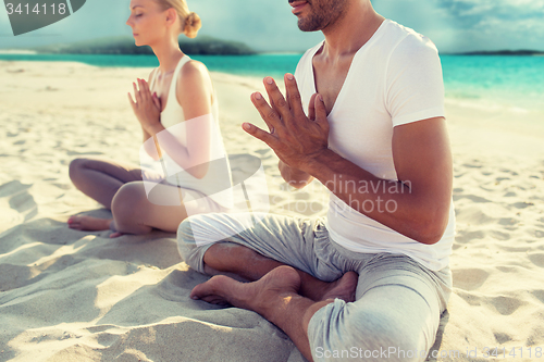 Image of smiling couple making yoga exercises outdoors