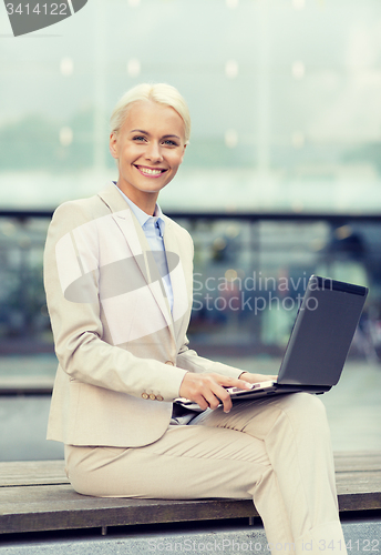 Image of smiling businesswoman working with laptop outdoors