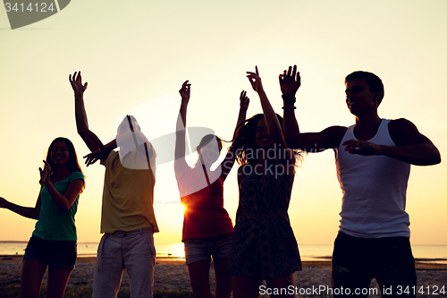 Image of smiling friends dancing on summer beach