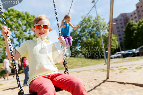 Image of two happy kids swinging on swing at playground