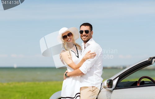 Image of happy man and woman hugging near car at sea
