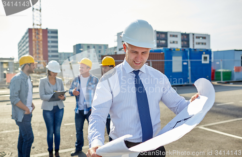 Image of architect with blueprint on construction site