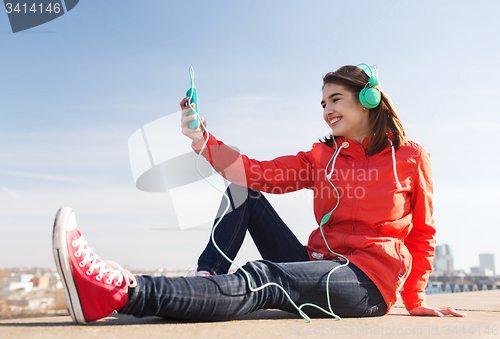 Image of happy young woman with smartphone and headphones