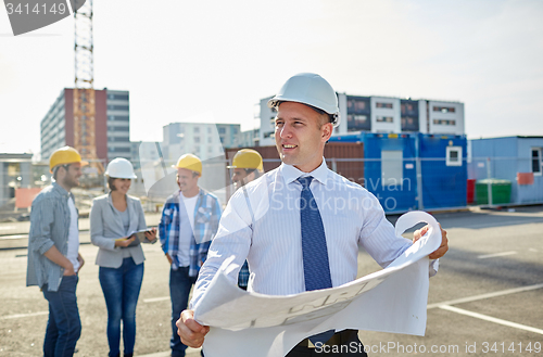Image of architect with blueprint on construction site
