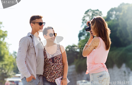 Image of happy friends with camera taking picture outdoors