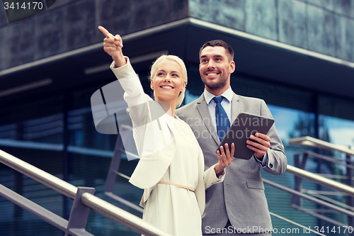 Image of smiling businessmen with tablet pc outdoors