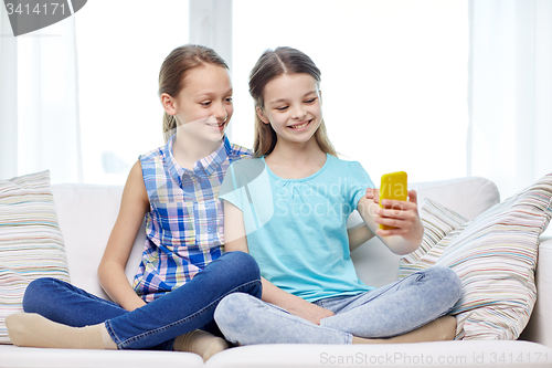 Image of happy girls with smartphone taking selfie at home