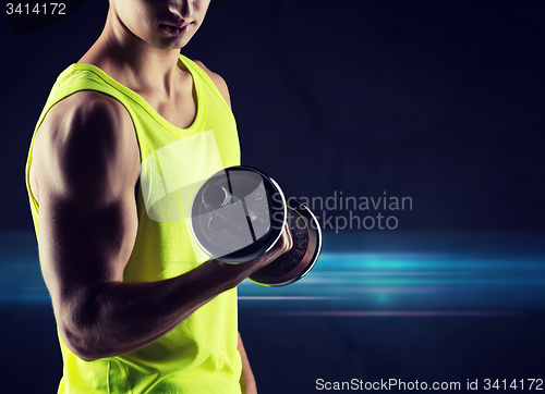 Image of close up of young man with dumbbell flexing biceps