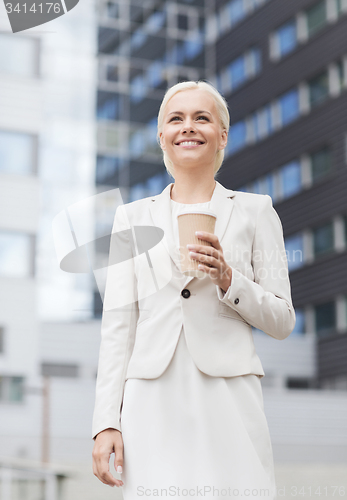 Image of smiling businesswoman with paper cup outdoors