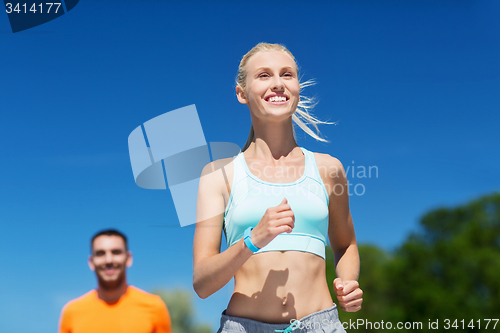 Image of smiling couple running outdoors