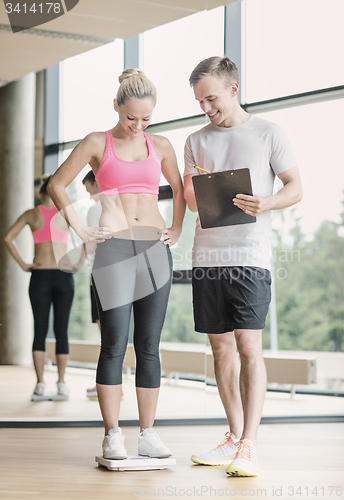 Image of smiling man and woman with scales in gym