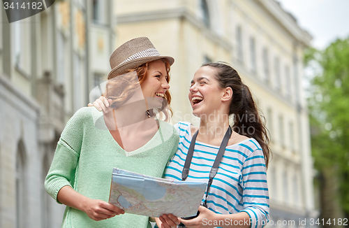 Image of smiling teenage girls with map and camera outdoors