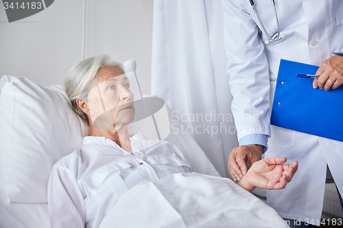 Image of doctor checking senior woman pulse at hospital