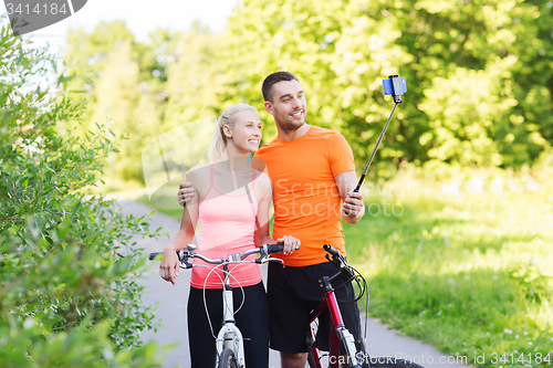 Image of couple with bicycle and smartphone selfie stick