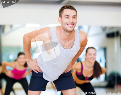 Image of smiling male trainer working out in the gym