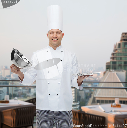 Image of happy male chef cook opening cloche